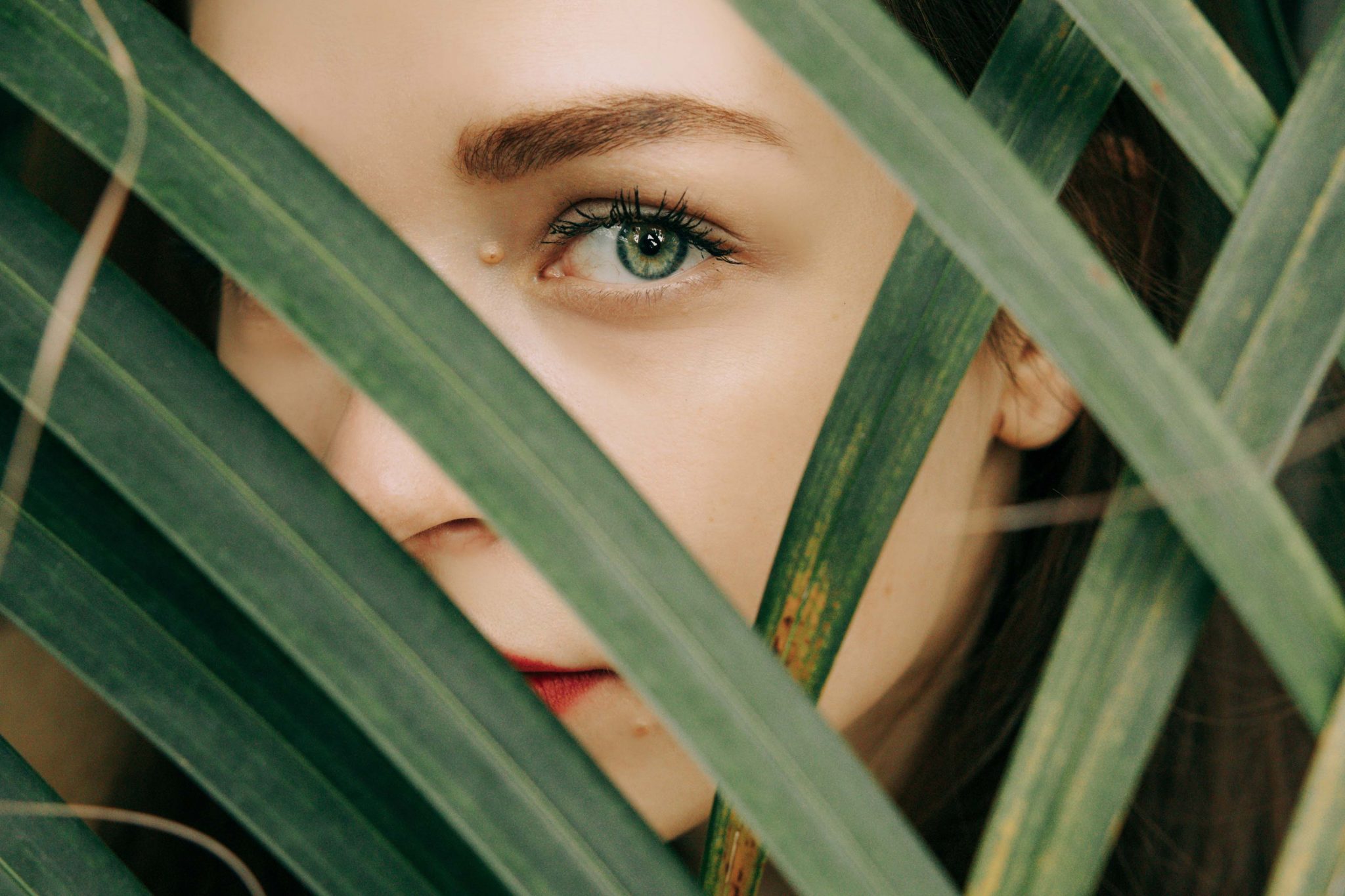 Woman looking through palm frawns