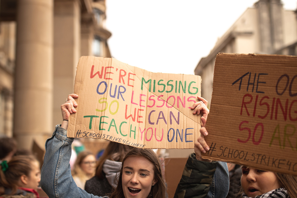 students holding signs protesting for the climate