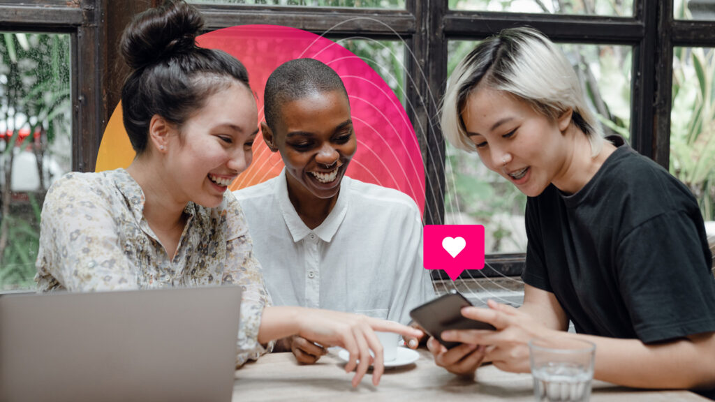 Earnings Conference Call Announcement;Three women sit at a table with a laptop looking at a smartphone