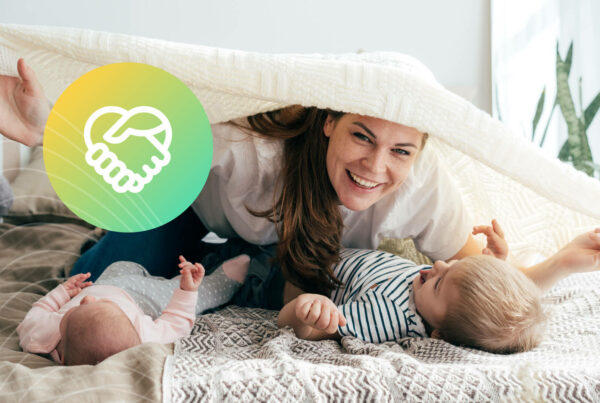 A mom plays with her baby on a bed