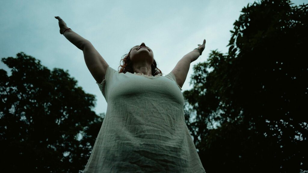 A woman with arms raised toward the sky