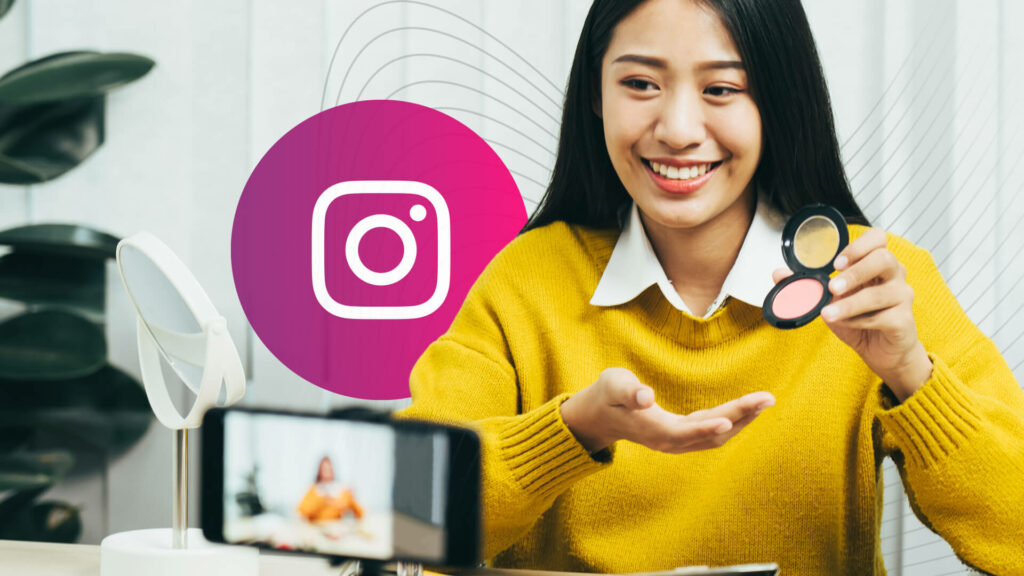 An AAPI influencer holds a blush while smiling in front of a phone on a tripod; Instagram logo