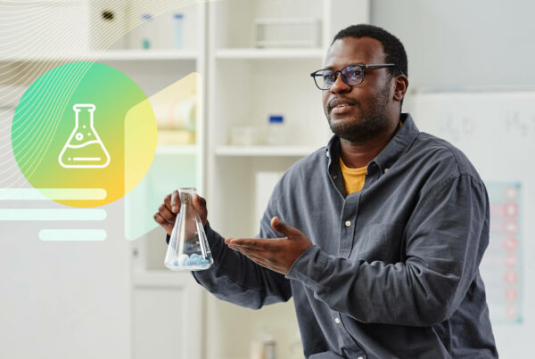 A scientist holds a beaker with blue liquid; he is a Black man in a gray long-sleeve top and orange undershirt and black glasses; STEM influencers
