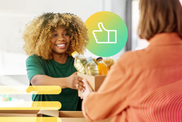 A woman with curly hair hands a box of donations to another woman