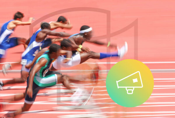 track and field athletes jump over a hurdle; the picture is blurred to illustrate their speed