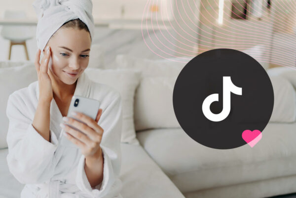 A female skincare influencer rubs her skin while taking a selfie on a white sofa; TikTok logo to the right