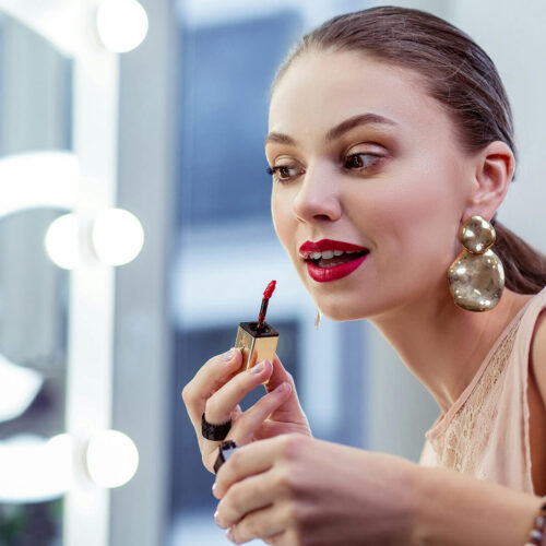 A makeup influencer puts on lip gloss