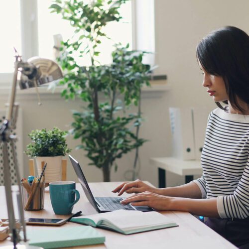 A woman works on a laptop at her desk