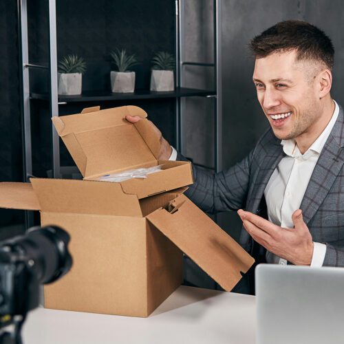 An influencer opens boxes in front of a camera
