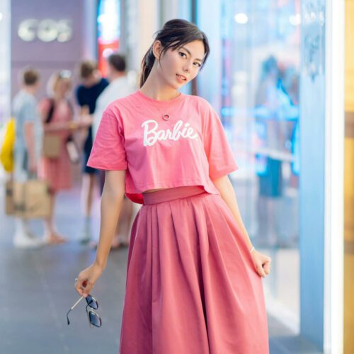A woman wearing a pink Barbie T-shirt and matching skirt