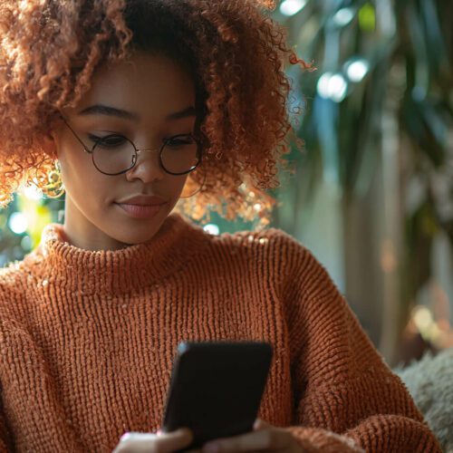 A woman with curly hair looks at her phone; Learn how to leverage influencers to cut through election-year ad clutter. Discover strategies for using authentic, engaging, and uplifting content to maintain consumer attention and stand out amidst the political noise during the election season.