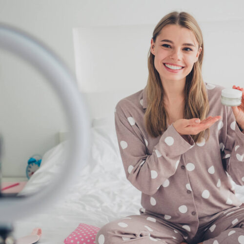 An influencer films a product video from her bed