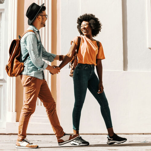 A man and woman hold arms while walking down a street